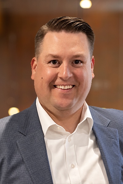 Smiling man in a blue blazer and white shirt, portrait-style corporate headshot indoors